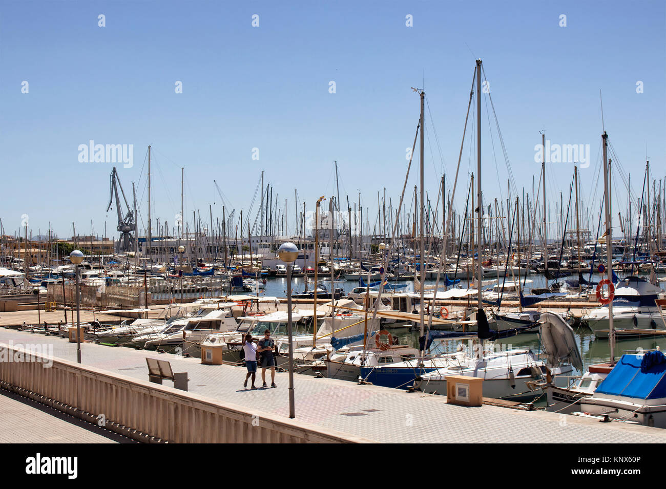 Two men walk at Palma de Mallorca marina in sunny summer day. It's a resort city and capital of the Spanish island of Majorca in the western Mediterra Stock Photo