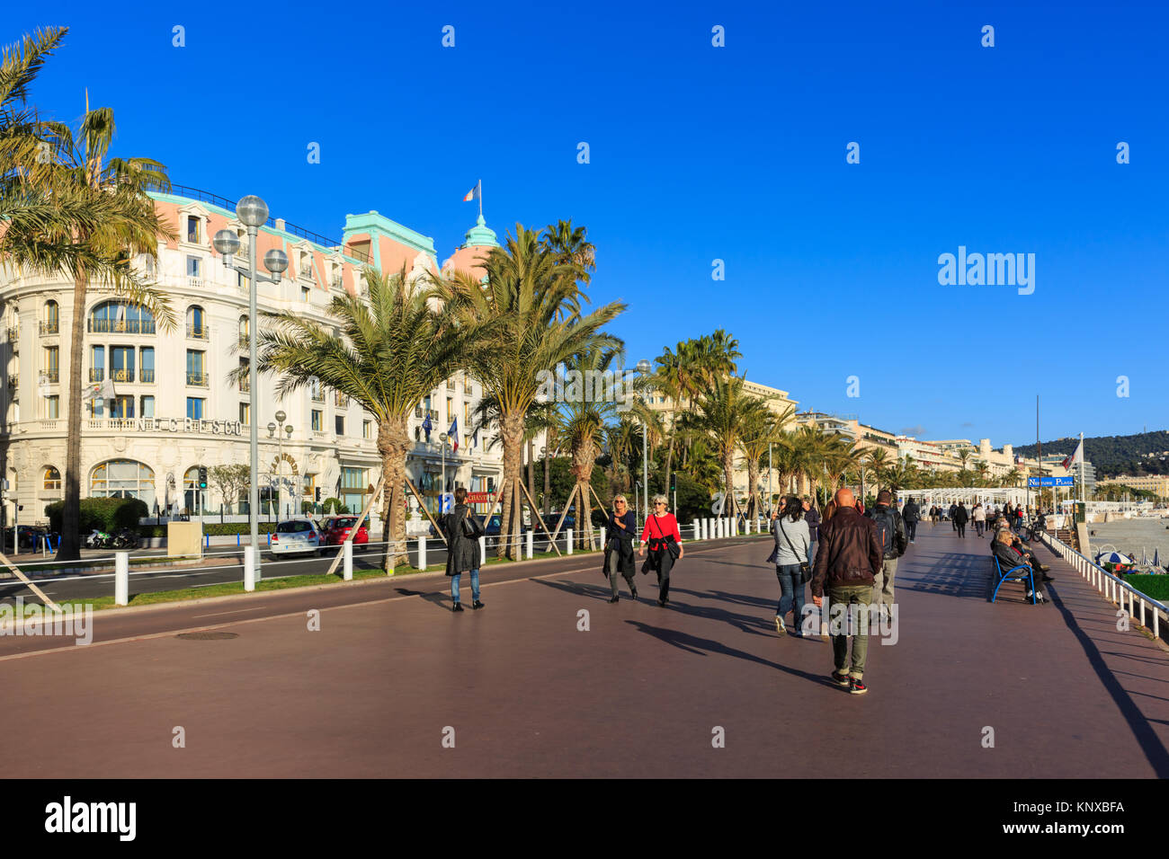 People walking in the sunshine on the seafront Promenade, Boulevard des Anglais, Nice, Cote d'Azur, France Stock Photo