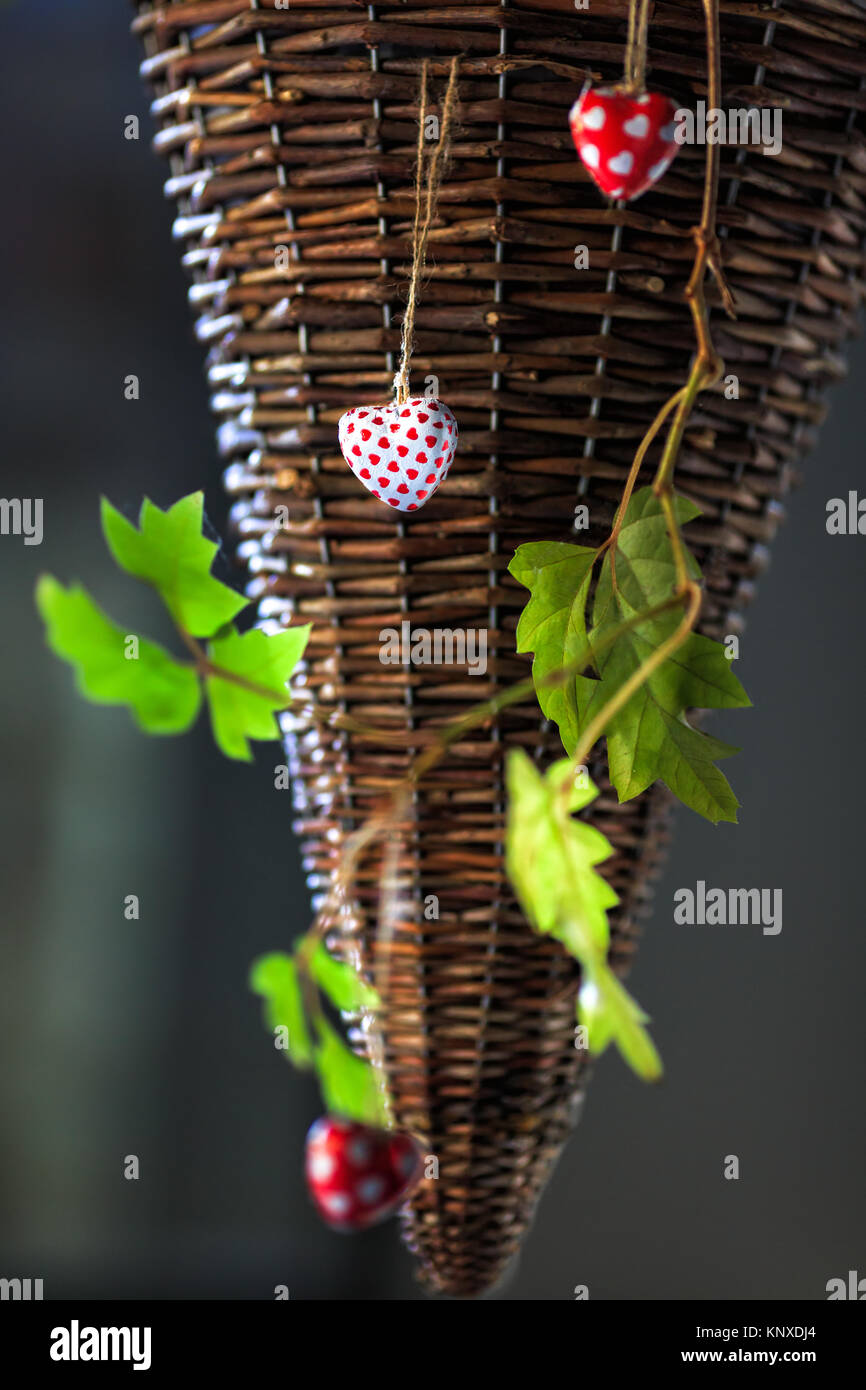 Beautiful hearts hanging on a rattan, flower pot with a green branch in the fresh air Stock Photo