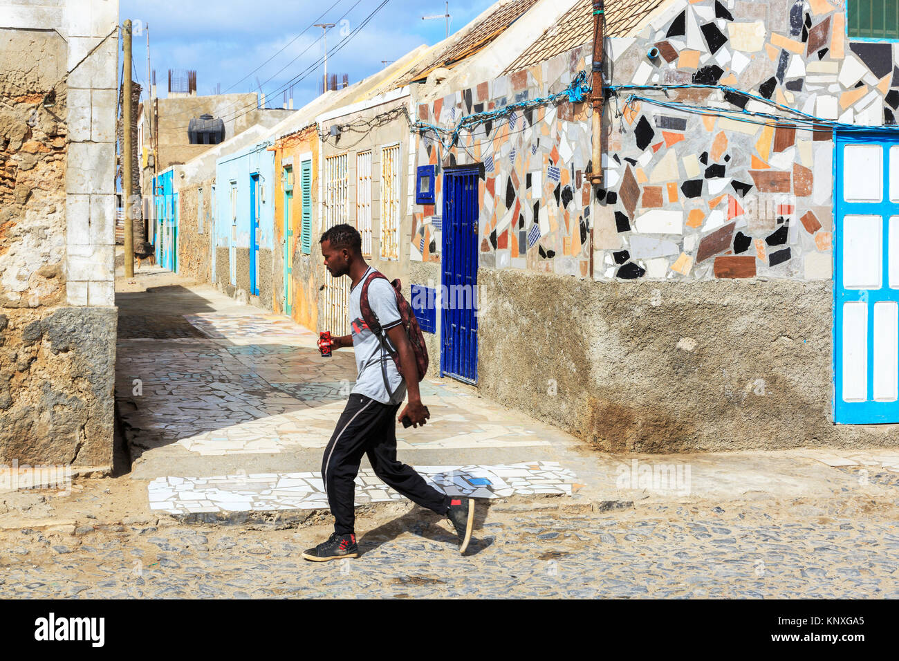 Local walking past traditional housing in a back street of Santa Maria, Sal, Salinas, Cape Verde, Africa Stock Photo