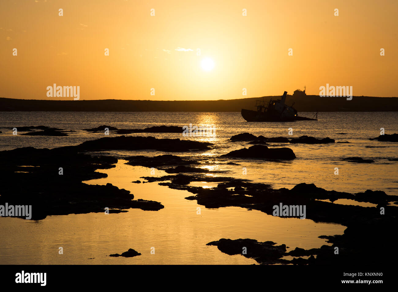 Sunset photo of shipwreck in shallow coastal water in the town of Sal Rei in Boa Vista Island, Cape Verde Stock Photo