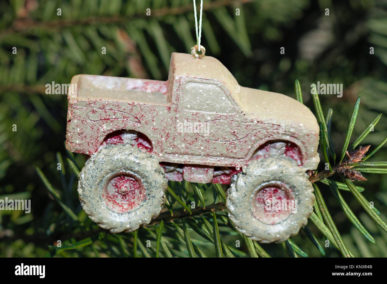Mud covered 4 wheel drive truck Christmas ornament with a few sparkles added hanging on real Christmas tree Stock Photo