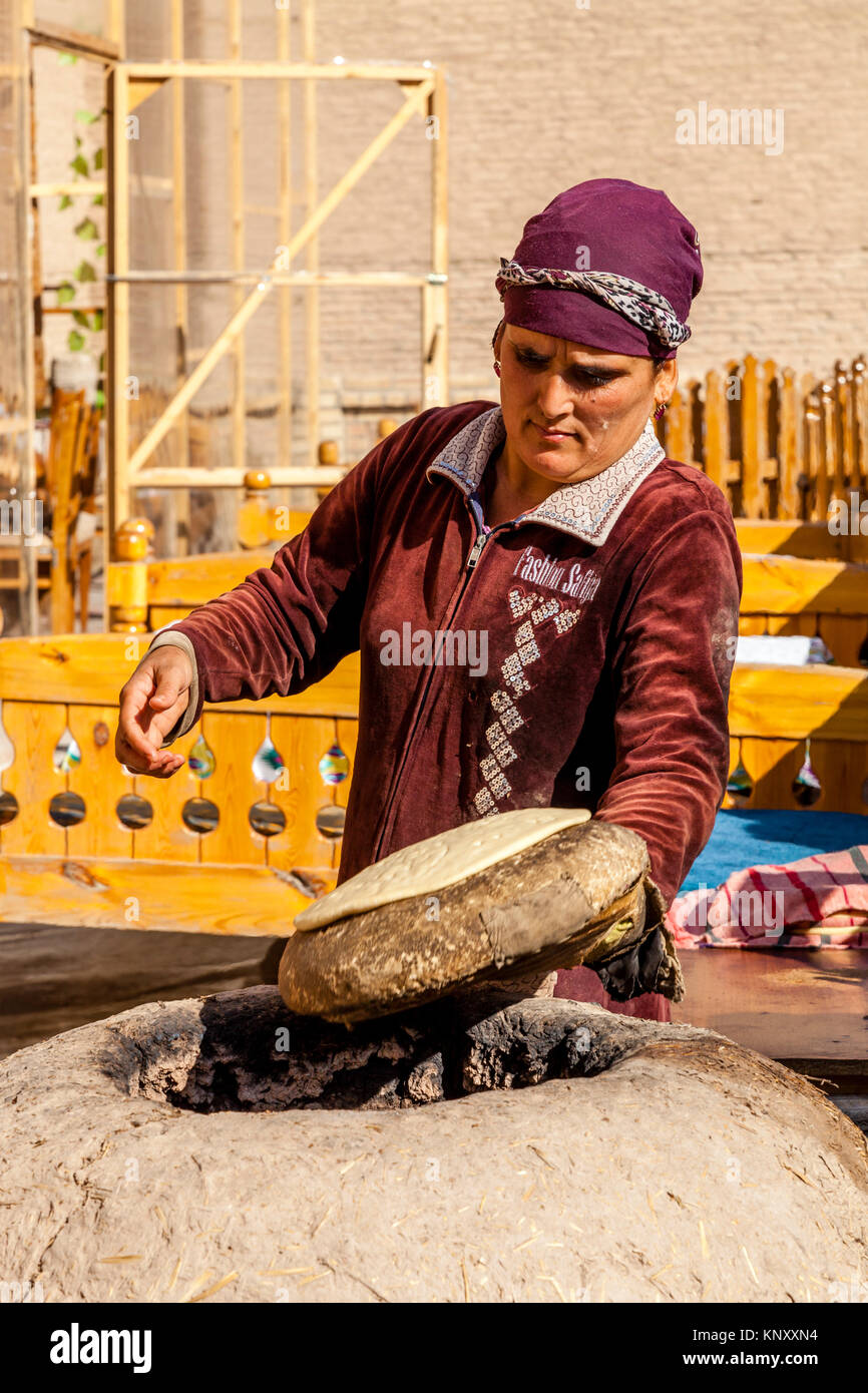 A Local Woman Bakes Bread In A Traditional Clay Oven, Khiva, Uzbekistan Stock Photo