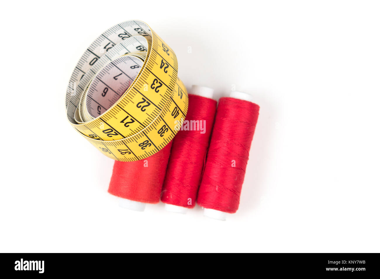 https://c8.alamy.com/comp/KNY7WB/sewing-supplies-red-thread-on-white-coil-and-yellow-measuring-tape-KNY7WB.jpg