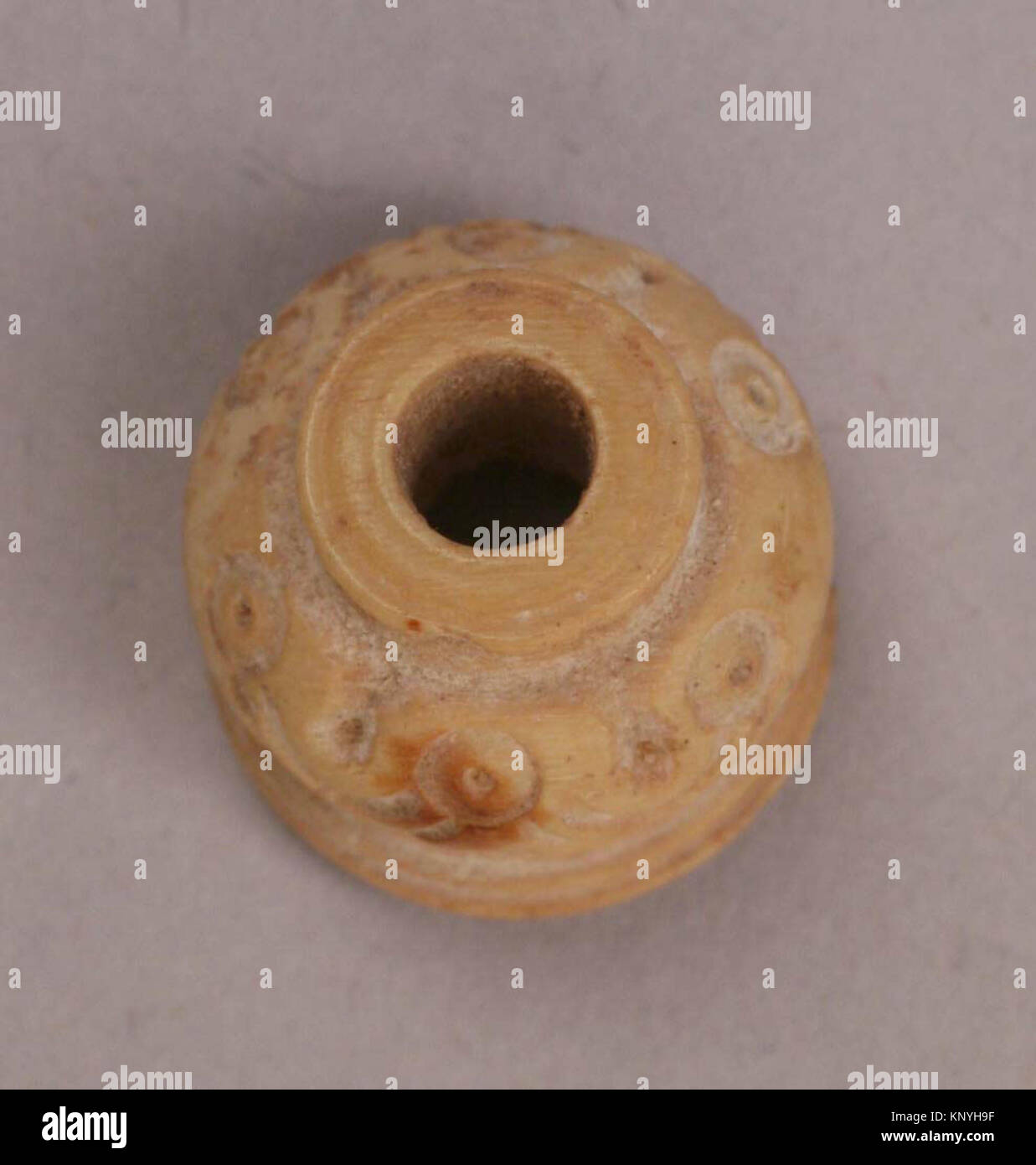 A small ancient button or bead, cataloged sf48-101-213z-a, held in the ...