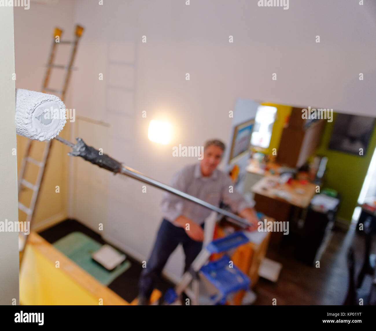 A decorator painting a house interior, difficult access involving scaffolding Stock Photo