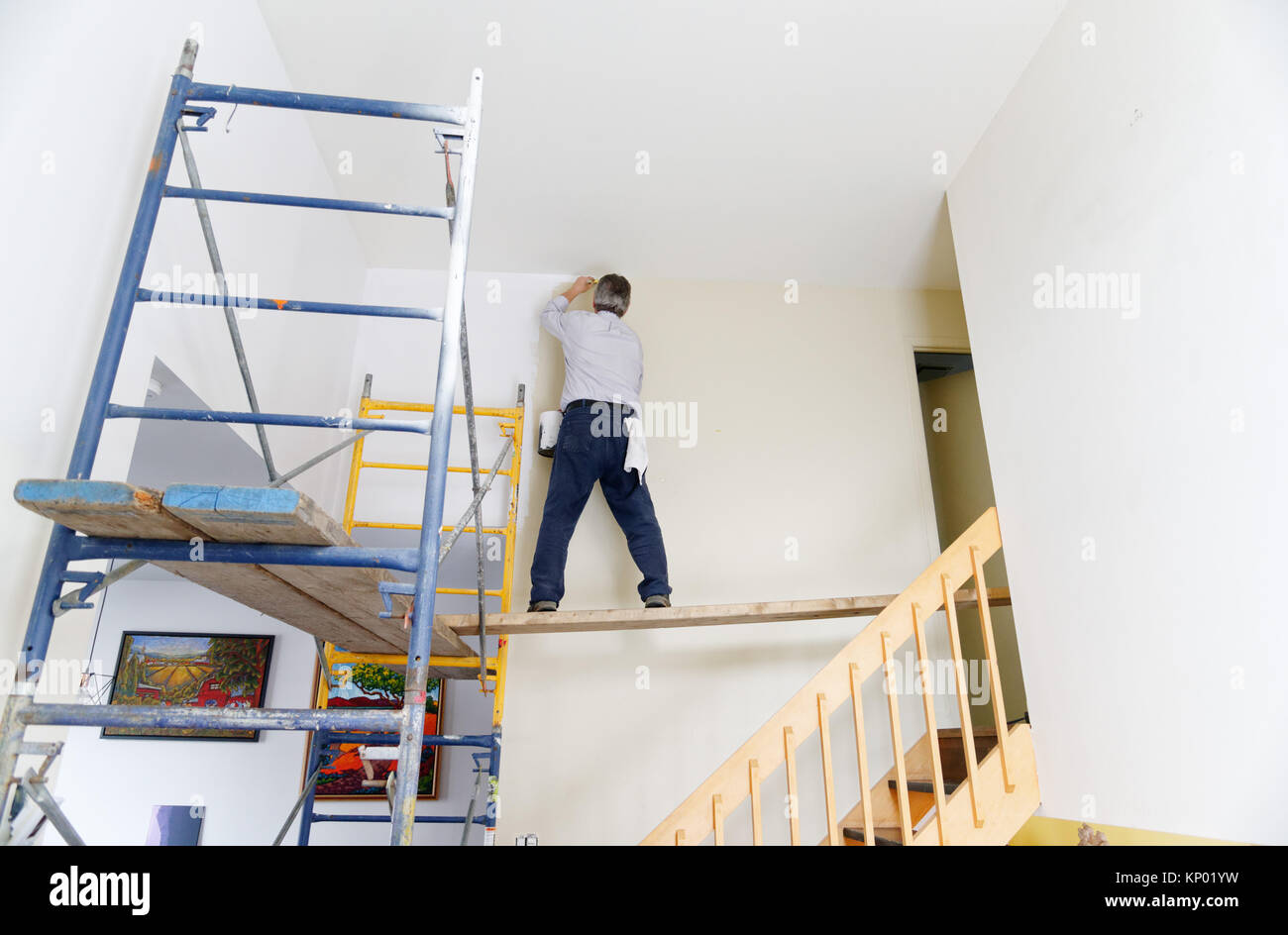 A decorator painting a house interior, difficult access involving scaffolding Stock Photo