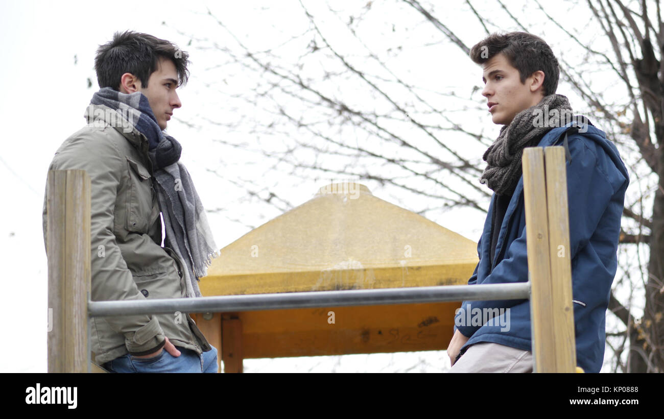 From below view of young men in winter clothing talking while chilling ...