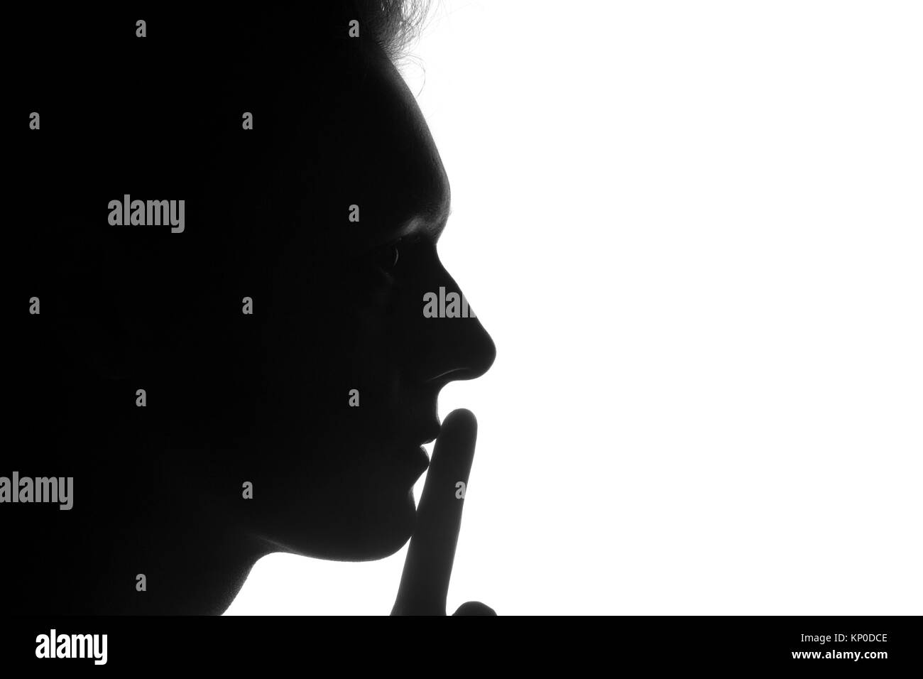 silhouette of a person in profile with a finger near the lips on a white background. Silens concept Stock Photo
