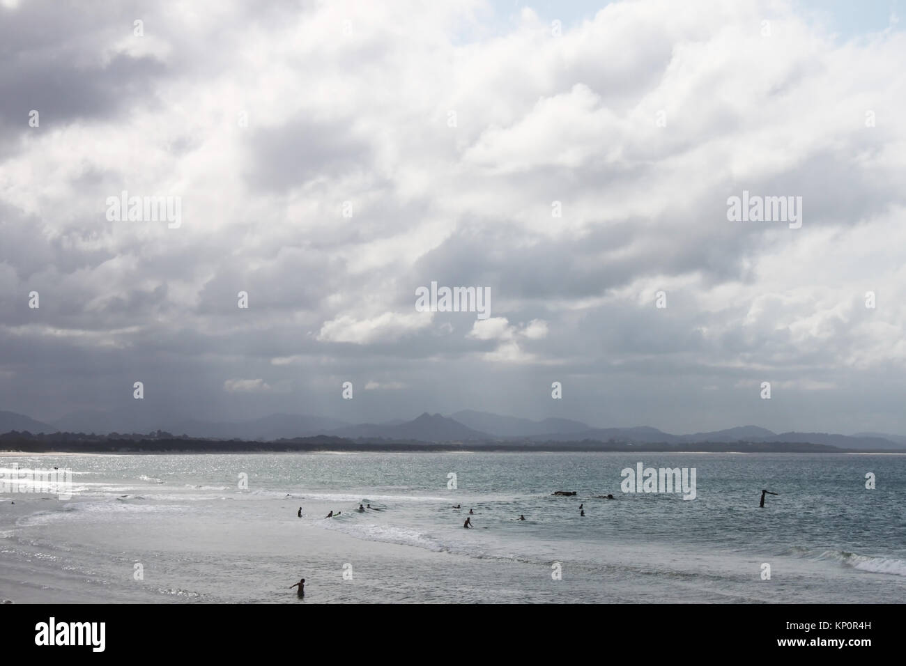 Swimmers out in grey ocean with waves on a stormy day in Byron Bay Australia Stock Photo