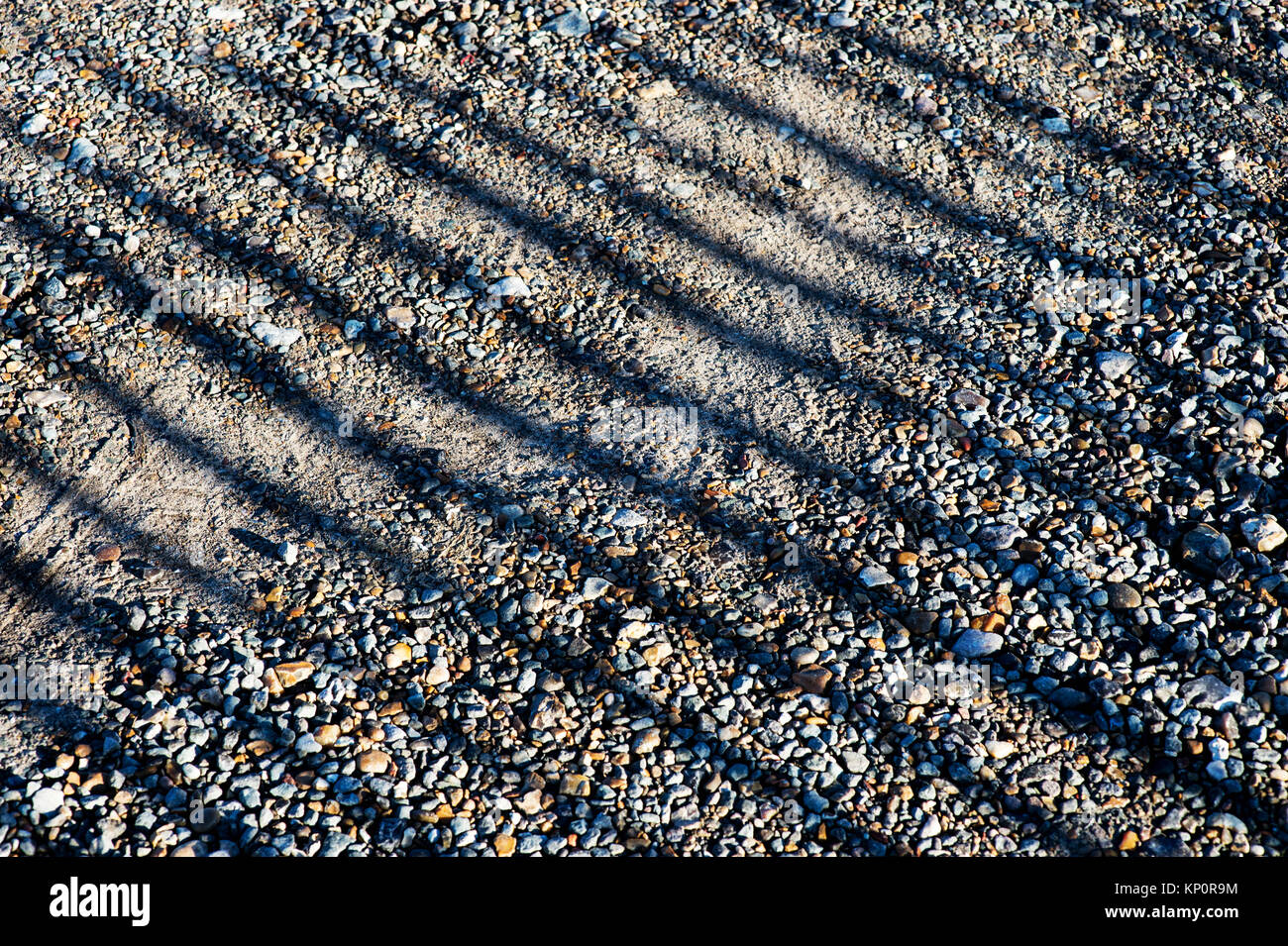 Shadows of a Wooden Fence on a Gravel Pathway Stock Photo