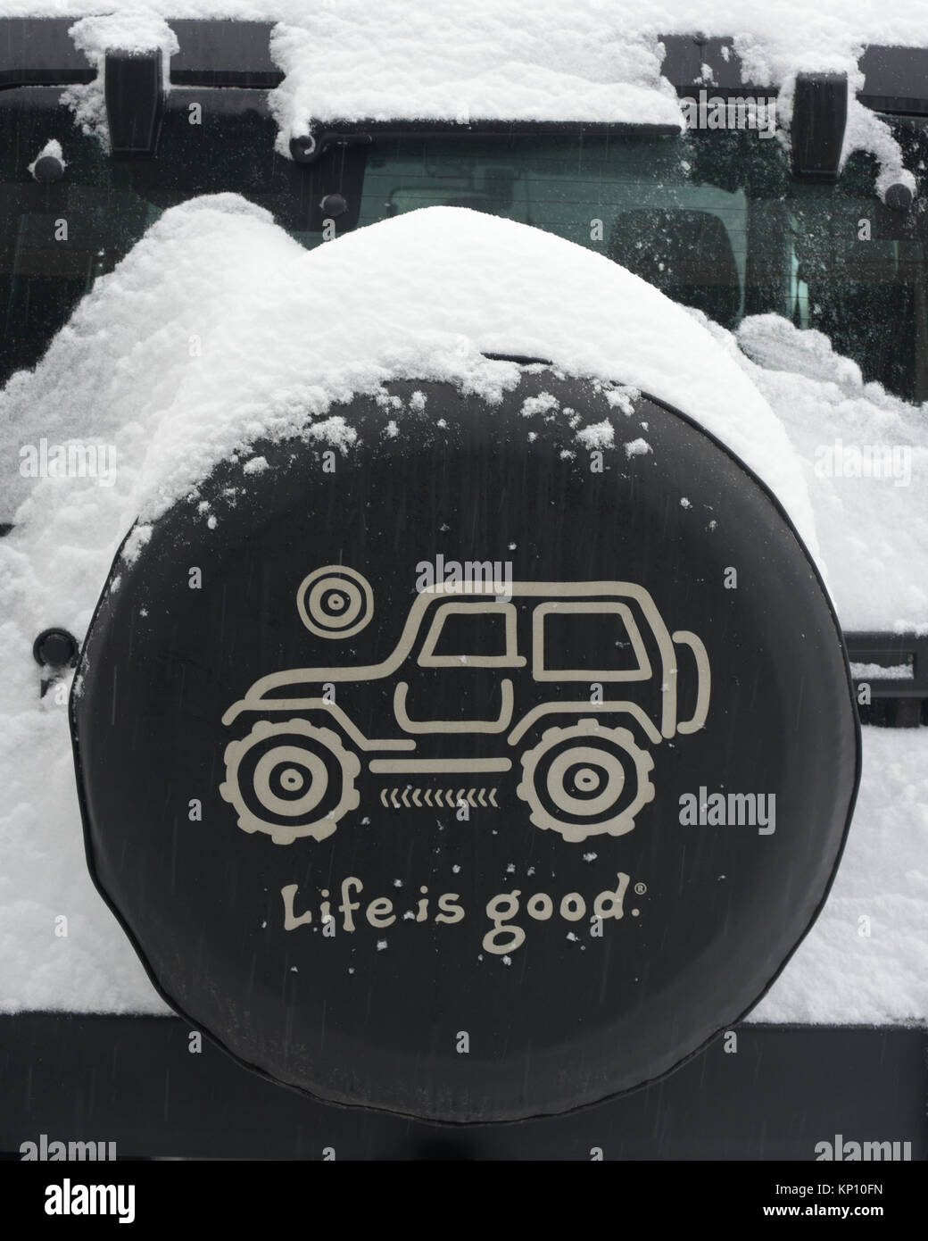 A Life is Good brand spare tire cover on the spare tire of a Jeep Wrangler in winter covered with snow in a snow storm in the Adirondack Mountains. Stock Photo