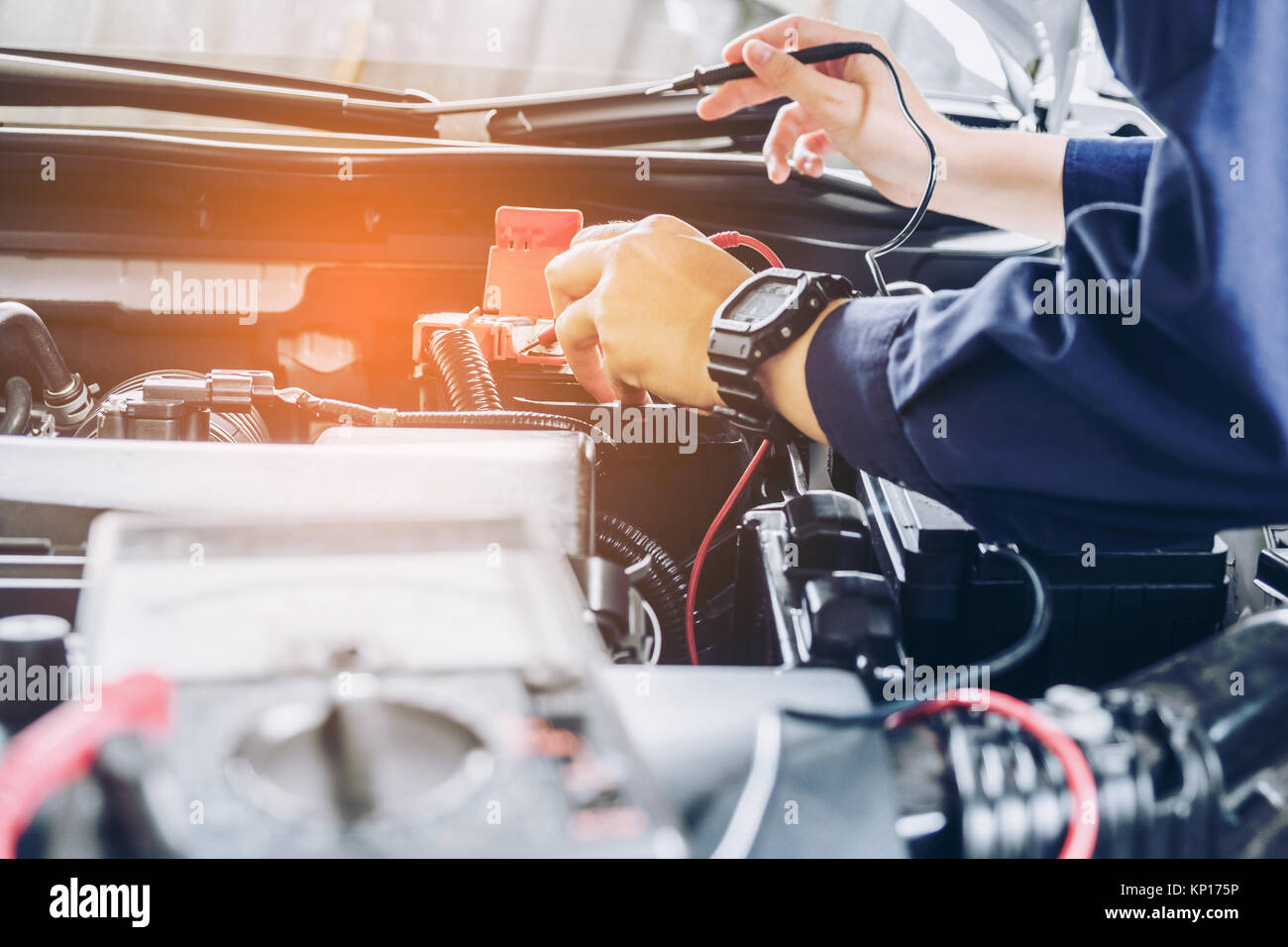 auto mechanic uses a multimeter voltmeter to check the voltage level in