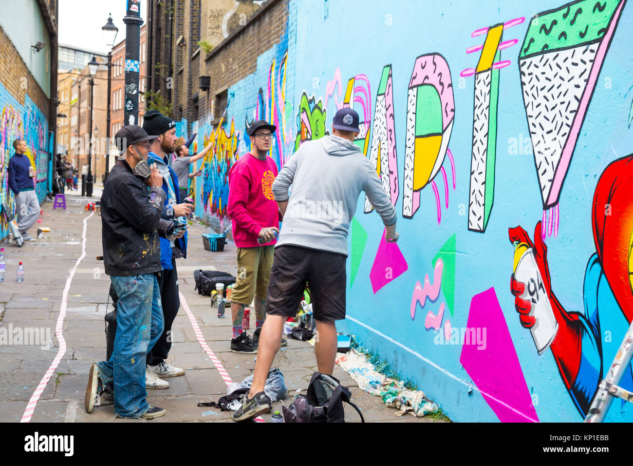 Graffiti street artists spraying the walls in Fleur Street, London, UK Stock Photo