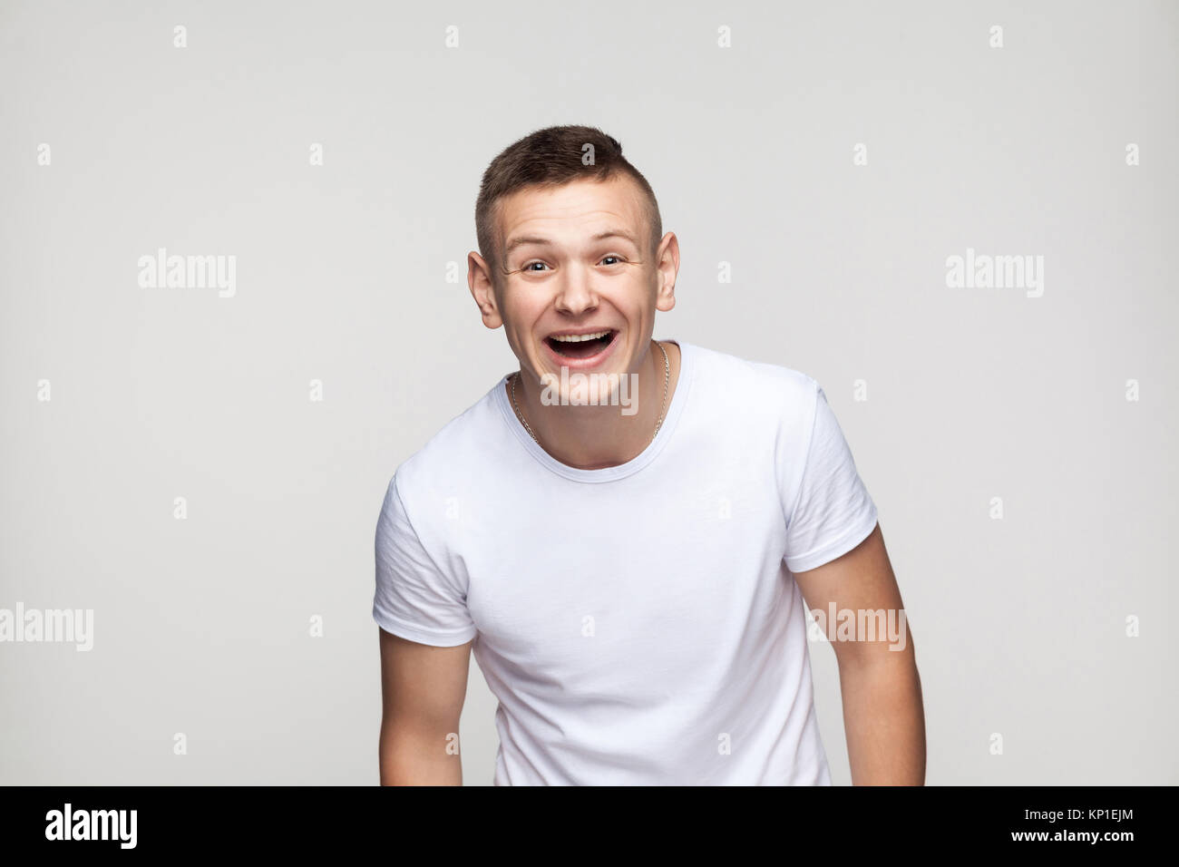 Young success man looking at camera and toothy smile. Studio shot, gray background Stock Photo
