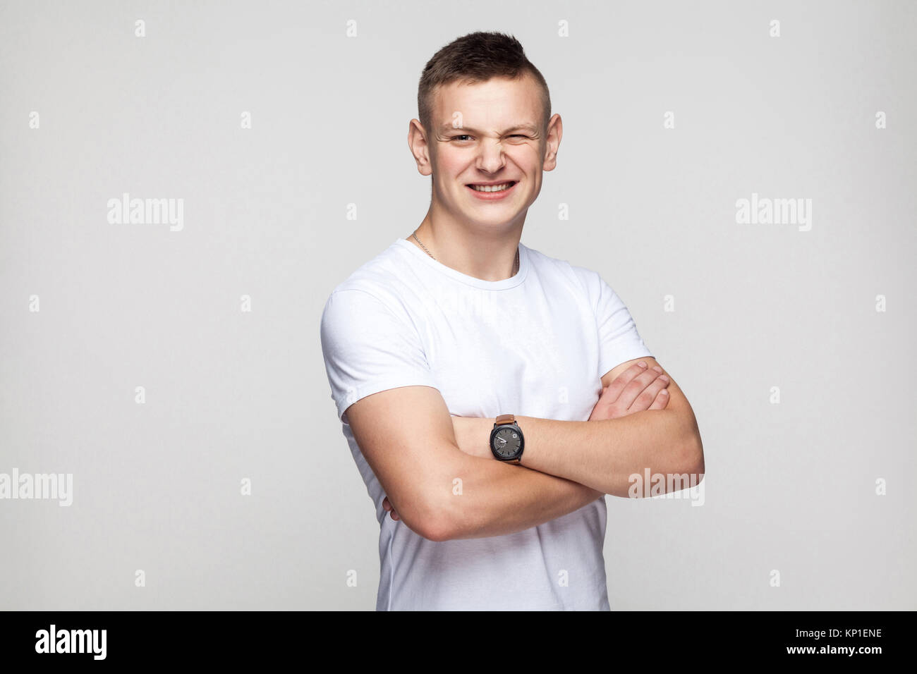 Boy crossed hands toothy smile and wink at camera. Studio shot Stock Photo