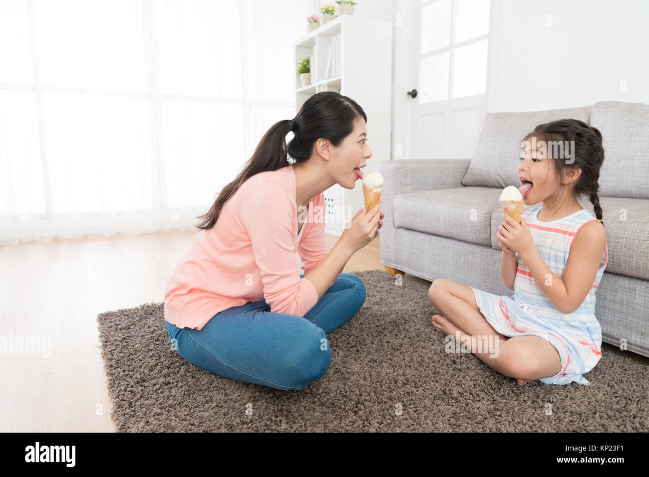 licking feet doughter happy pretty mother sitting on living room floor with lovely beauty daughter  licking ice cream enjoying summer season at home Stock Photo - Alamy