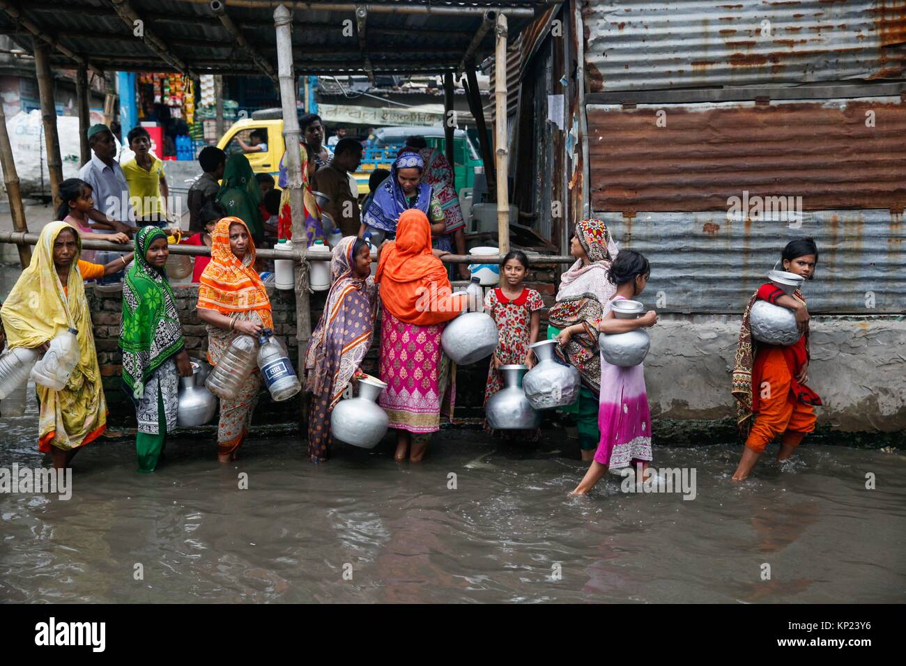 Bangladeshi women and kids are busy to collecting drinking water from a polluted water logged area in Dhaka on June 17, 2017. Stock Photo