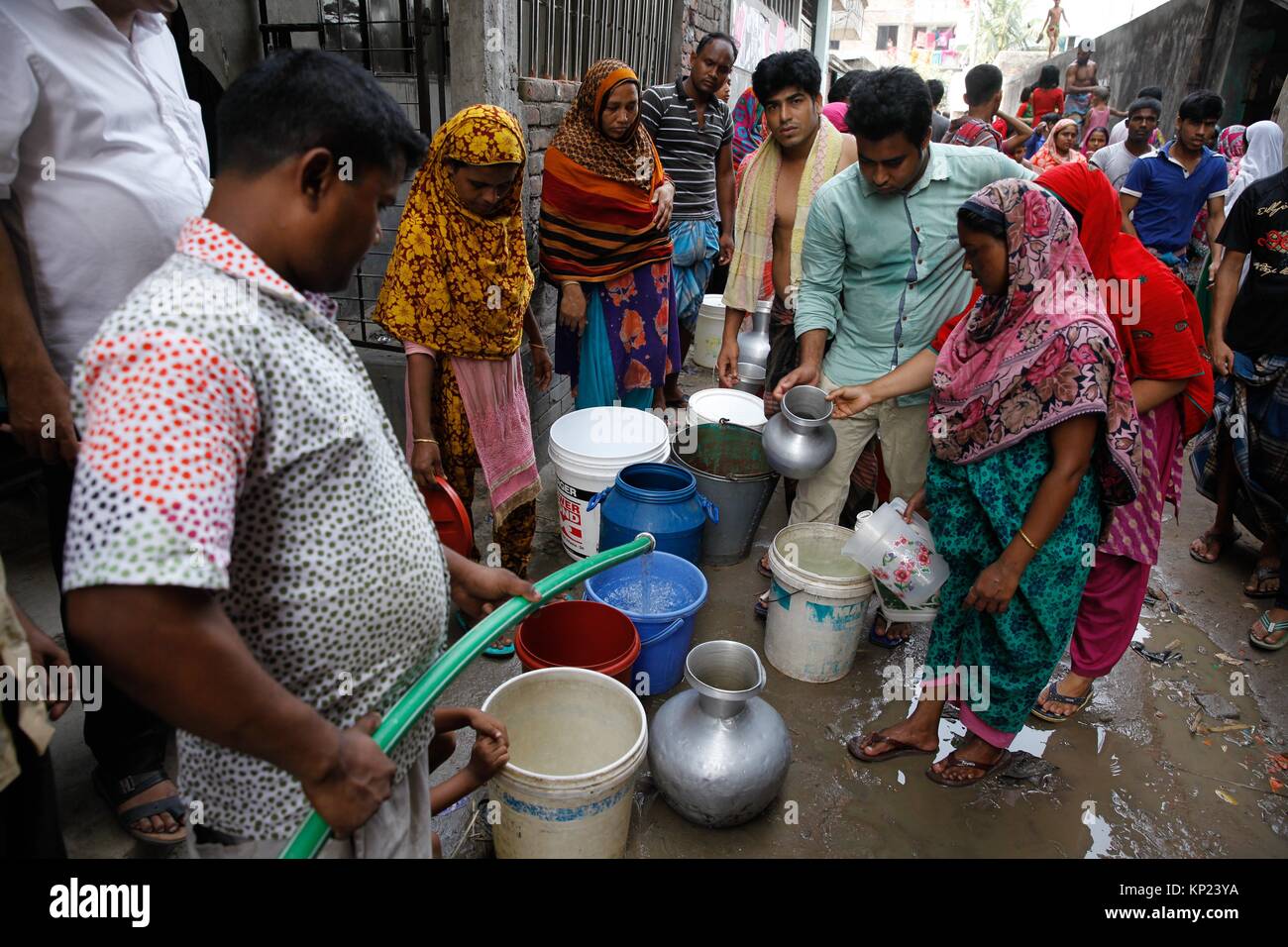 Bangladeshi women and children waiting for drinking water inside the street in Dhaka. Water crisis has been seen in the most under developing and Stock Photo