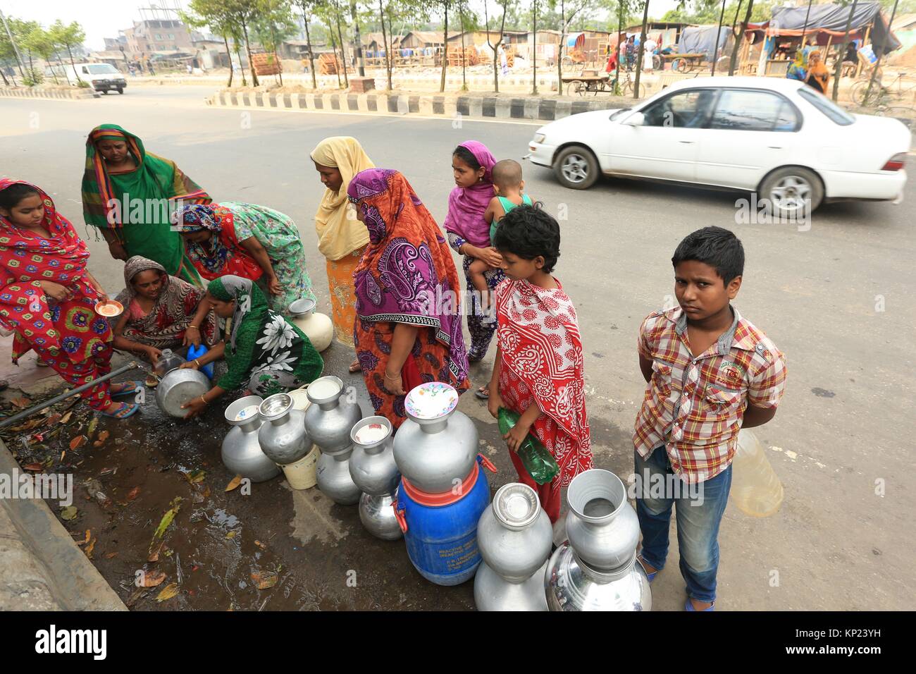 Bangladeshi women and children waiting for drinking water inside the street in Dhaka. Water crisis has been seen in the most under developing and Stock Photo