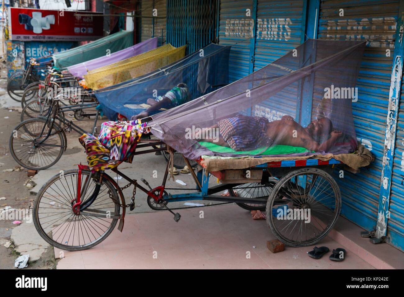 Bangladeshi three wheeler puller shelter in mosquitoâ.s net during their sleep to safe himself from mosquito beside the street at Dhaka. As Stock Photo