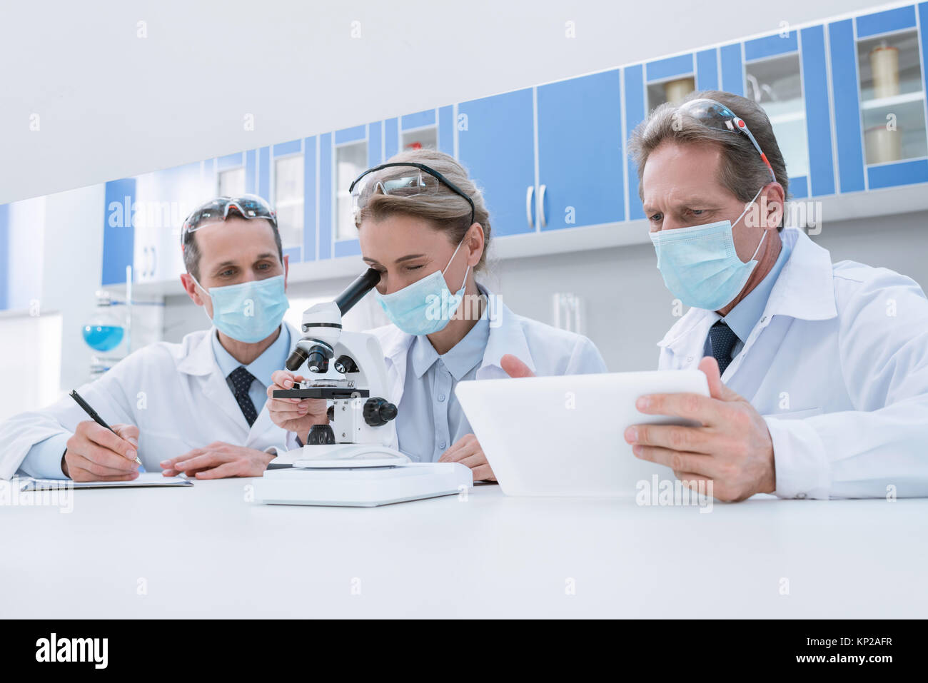 Scientists working with microscope and tablet Stock Photo - Alamy