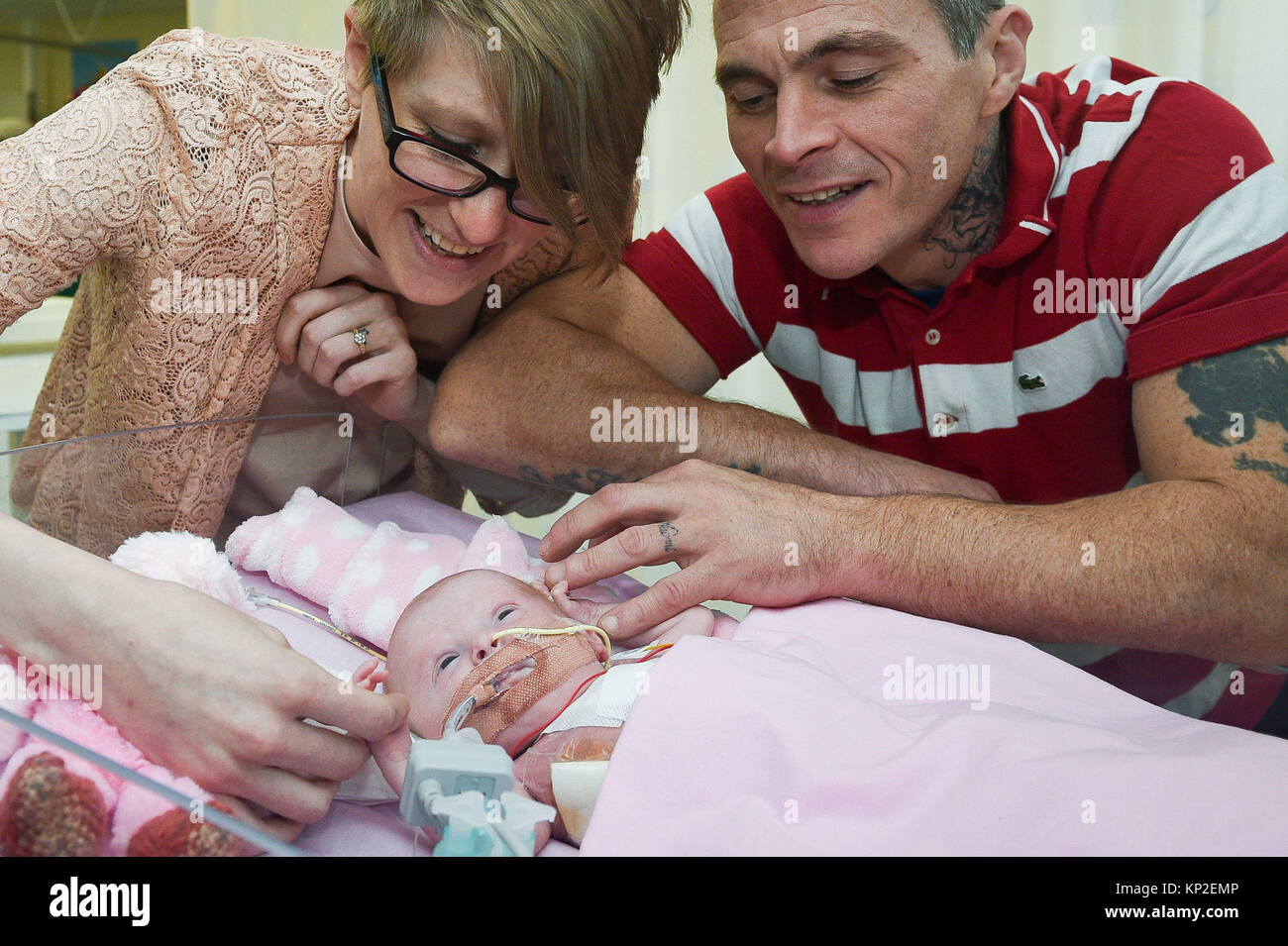 Three-week-old Vanellope Hope Wilkins, who was due to be delivered on Christmas Eve before an incredibly rare condition, in which the heart grows on the outside of the body, meant she had to be born prematurely by caesarean section on November 22, is caressed and touched by her parents Naomi Findlay and Dean Wilkins, at Glenfield Hospital in Leicester, after surviving, in what is believed to be a UK first. Stock Photo