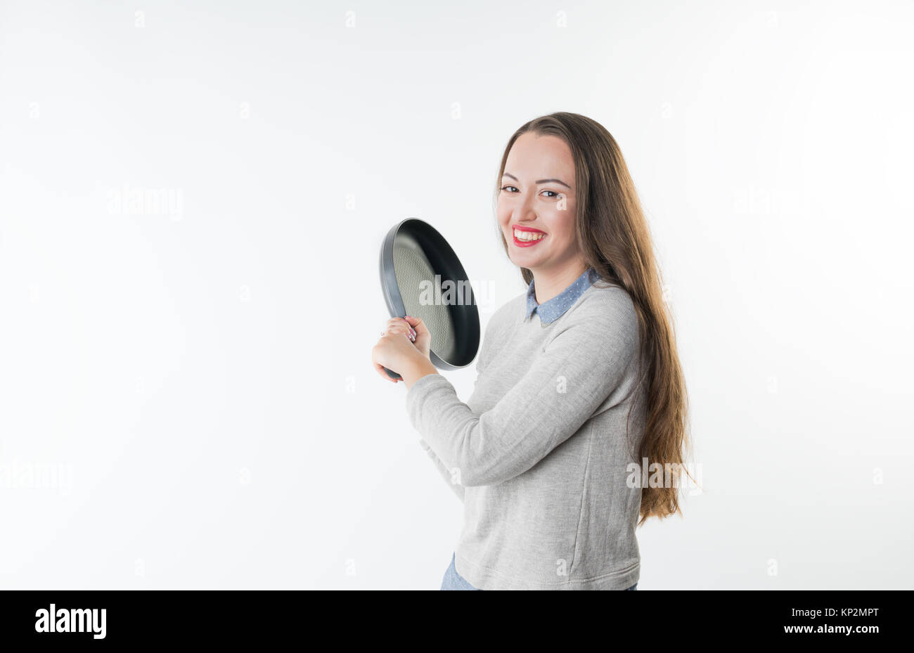 Angry smiling woman with insult laugh on her face and frying pan Stock Photo