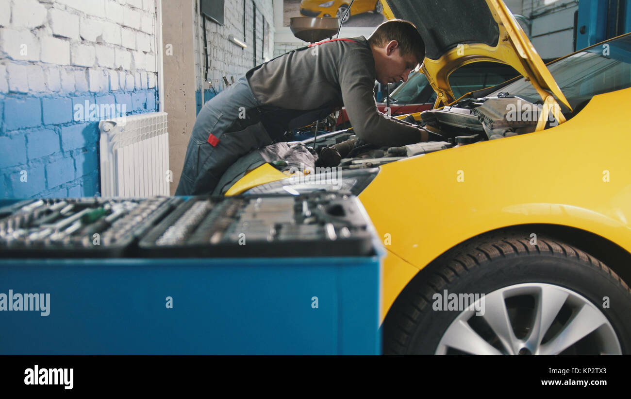 Mechanic in car service repairing in engine compartment Stock Photo