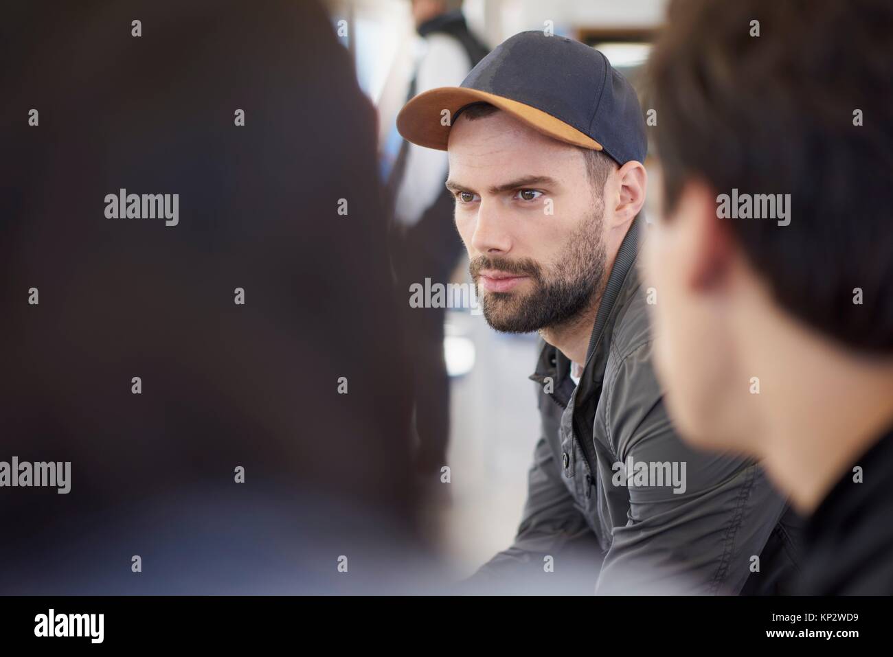 Thoughtful, distracted young man is daydreaming during conversation with friends Stock Photo