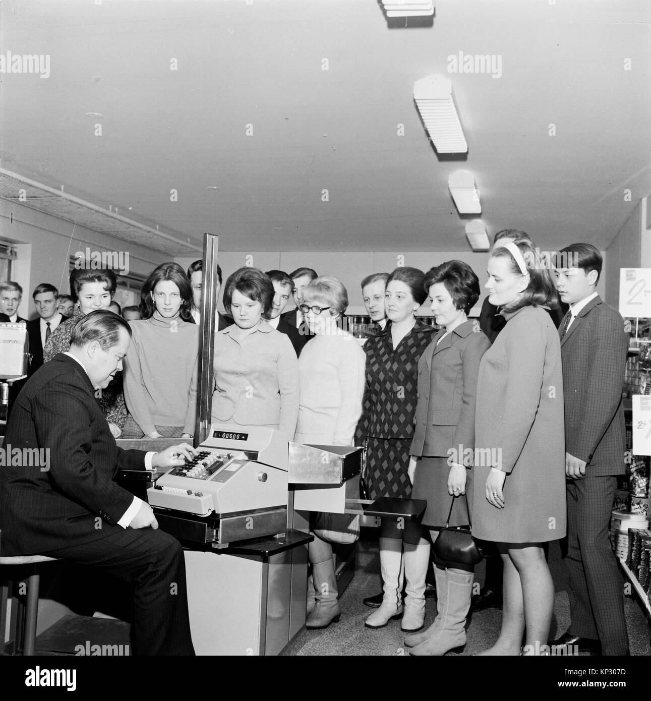 Man demonstrating use of modern cash register till watched by shop staff, Helsinki, Finland, 1960s Stock Photo