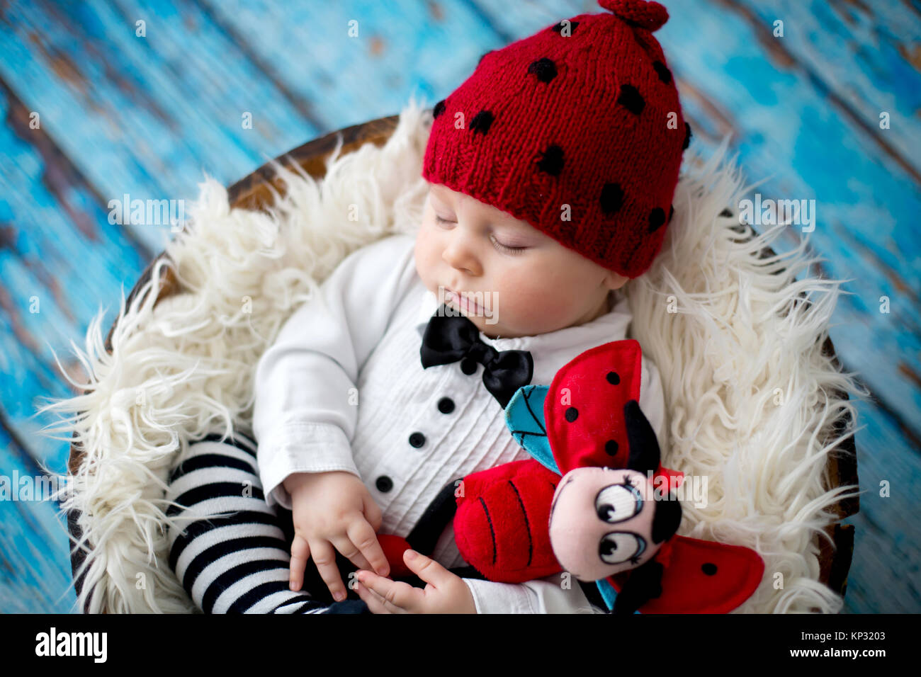 Little baby boy with knitted ladybug hat and pants in a basket, sleeping peacefully in a basket, isolated studio shot Stock Photo