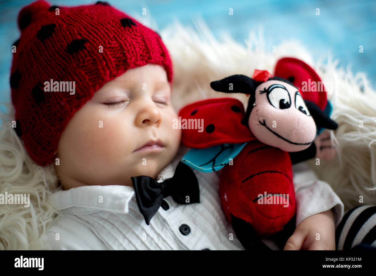 Little baby boy with knitted ladybug hat and pants in a basket, sleeping peacefully in a basket, isolated studio shot Stock Photo