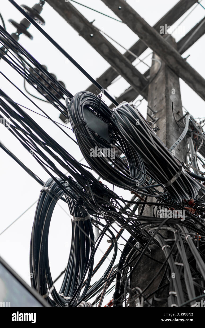 picture of a close-up of randomly hanging wires on electric poles in Thailand Stock Photo