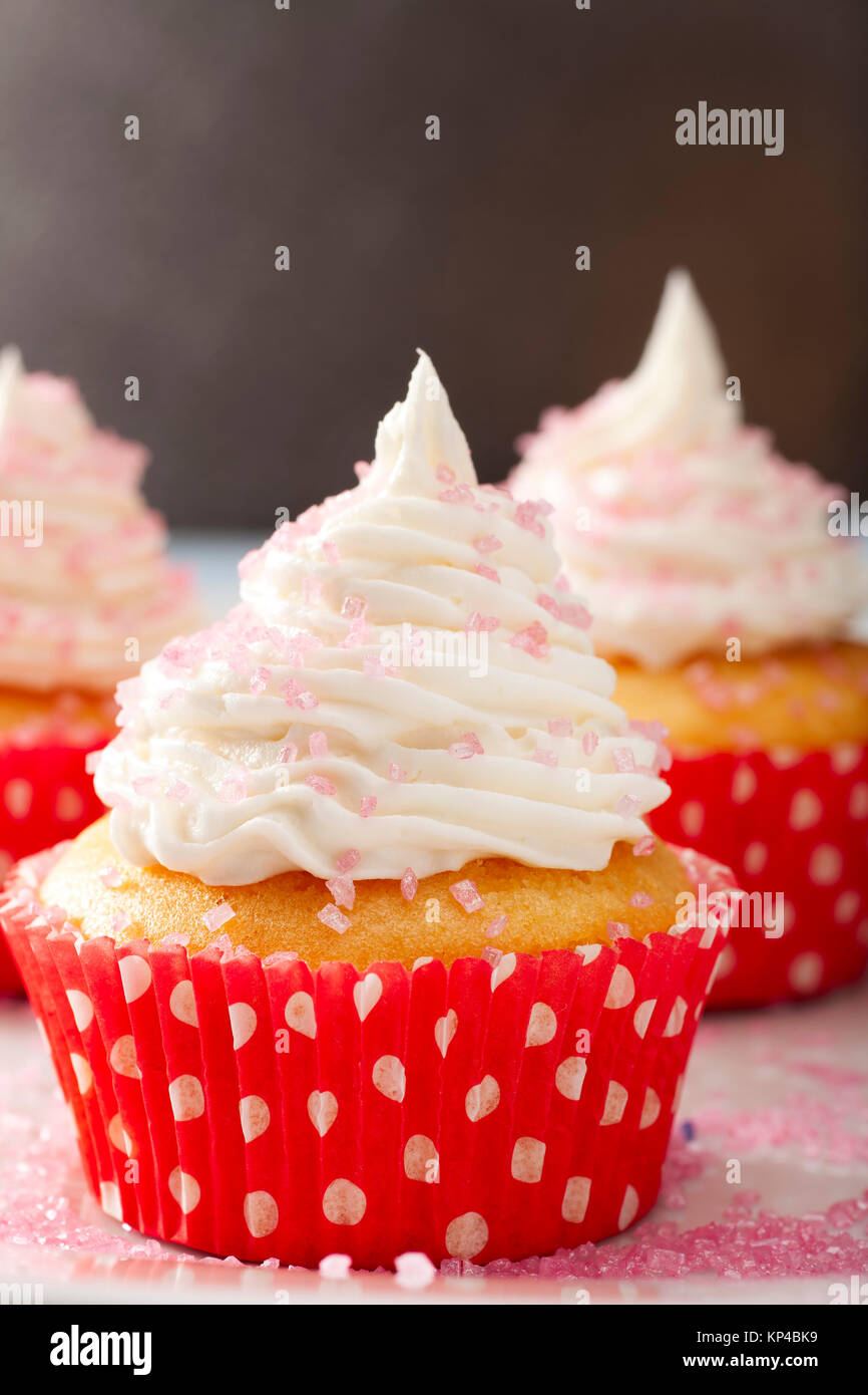 Yellow cupcake in red and white polka dot cupcake paper topped with white frosting Stock Photo