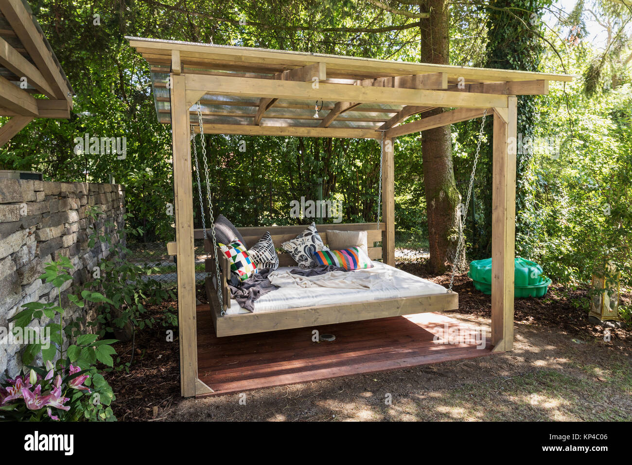 Big swing outdoor bed. Chaise longue in the garden in the pergola. Garden  bed with pillows. Big outdoor bed for sunbathing and rest. Four garden bed  Stock Photo - Alamy