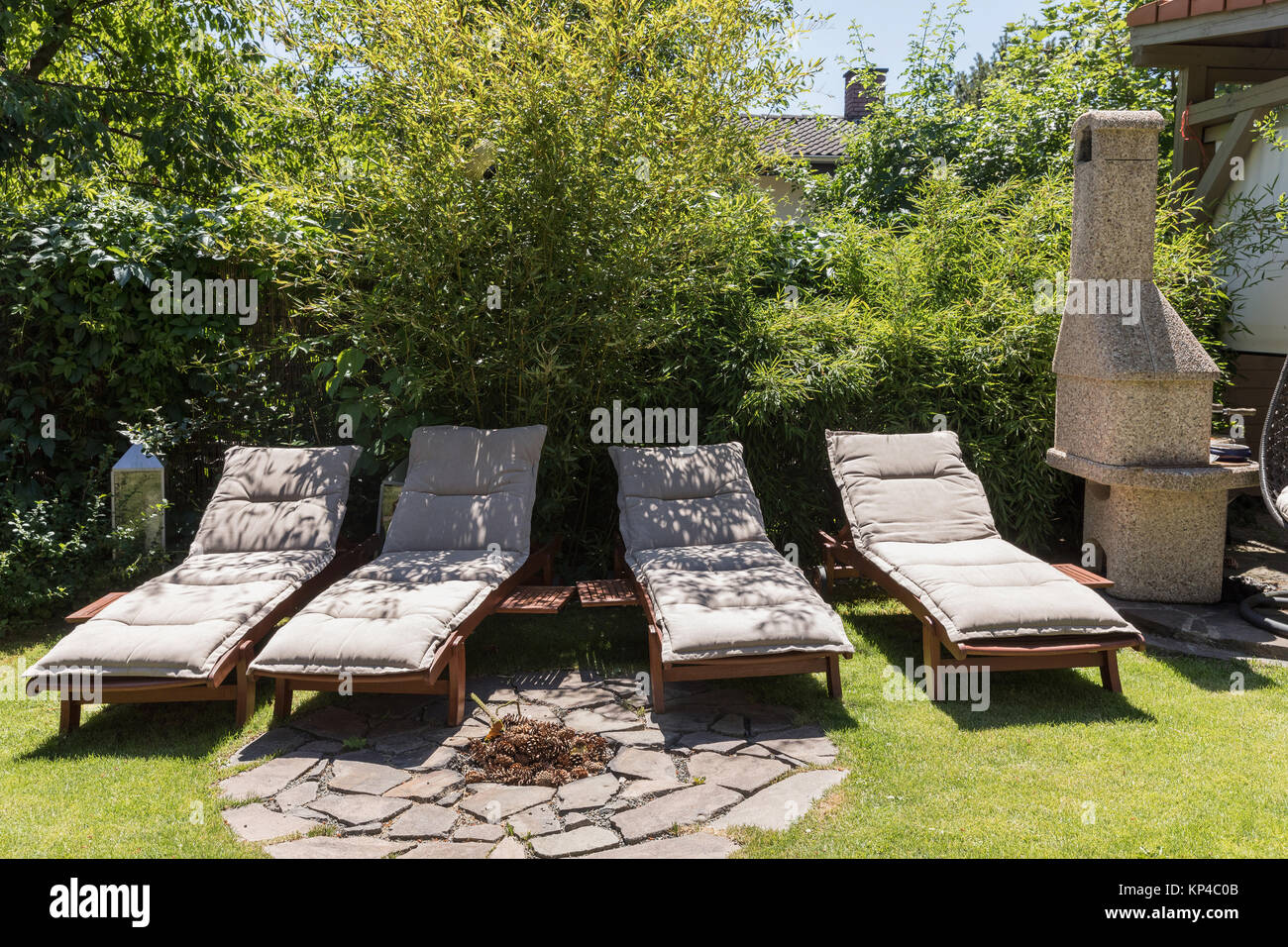 Garden sunbeds on green grass, bamboo fence background. Garden bed for sunbathing and rest. Four