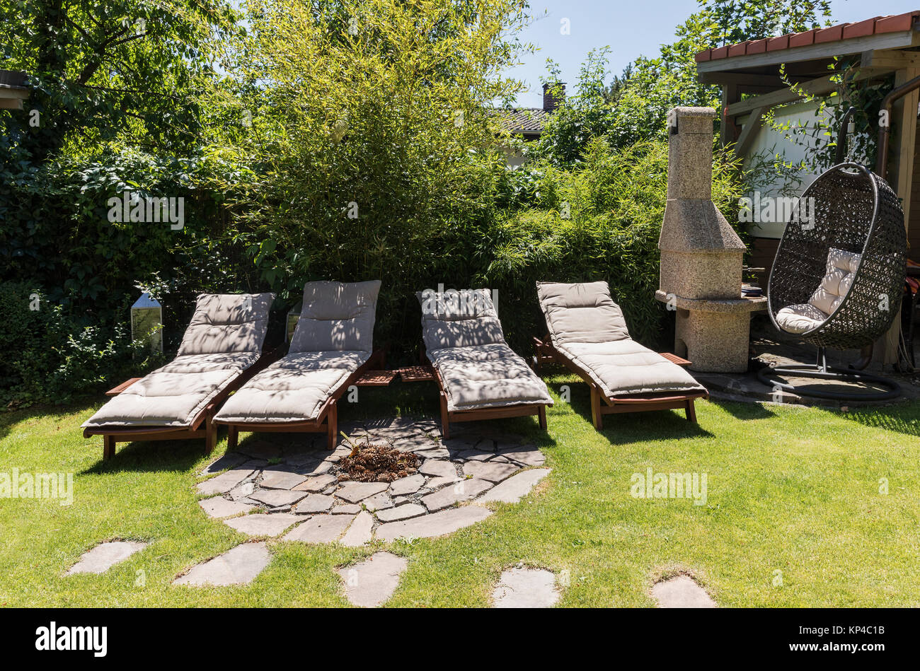 Garden sunbeds on green grass, bamboo fence background. Garden bed for