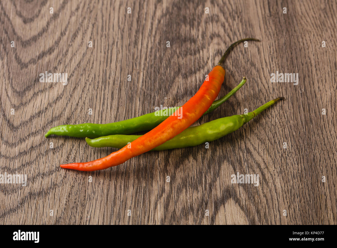 Chili peppers over the wooden background Stock Photo - Alamy