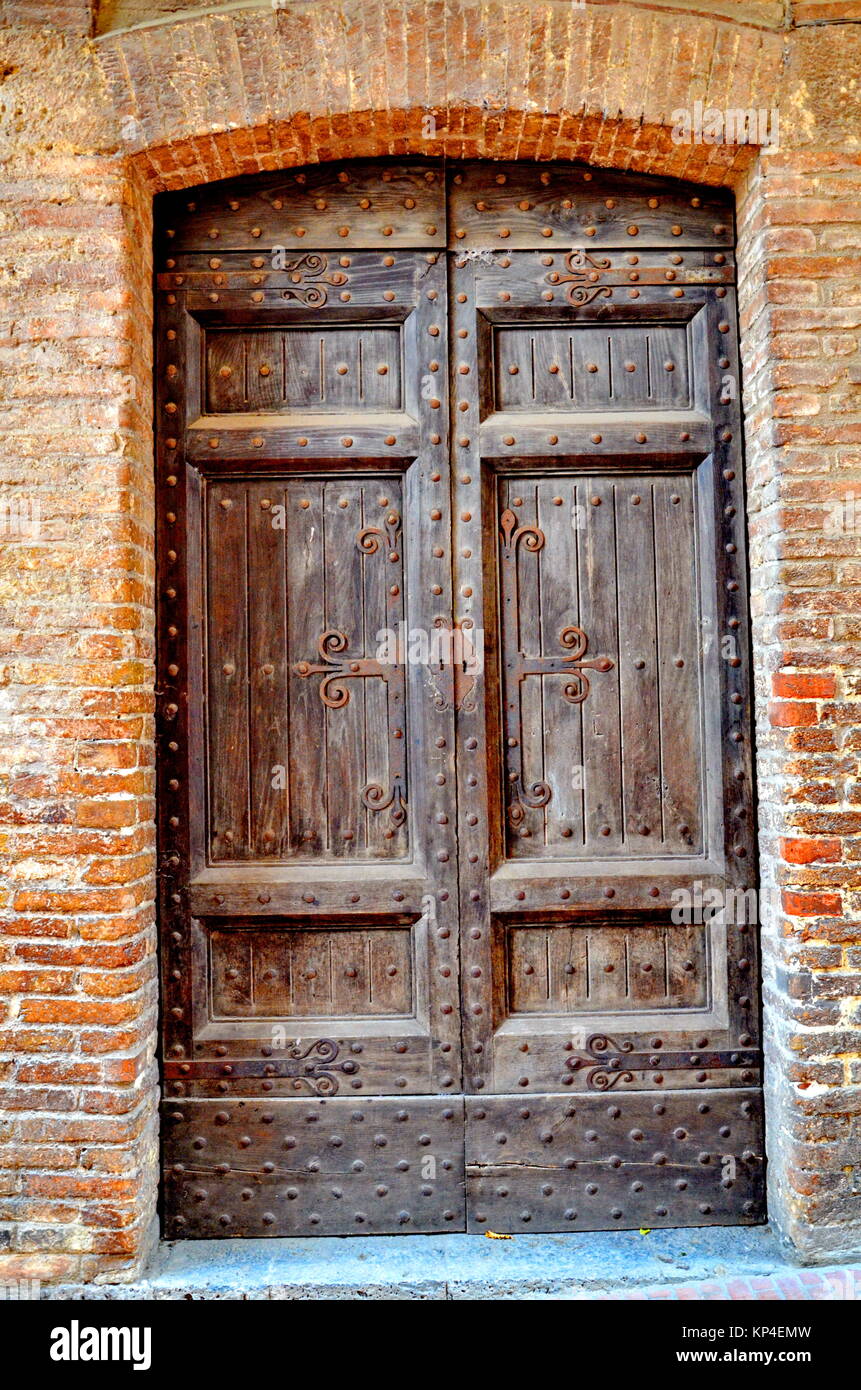 Old wood Door and brick wall, San Gimignano, Tuscany, Italy Stock Photo