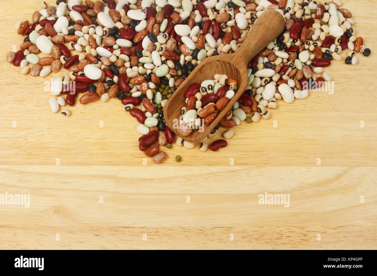 Ten dried bean mix with a wooden scoop on a chopping board with copy space below Stock Photo