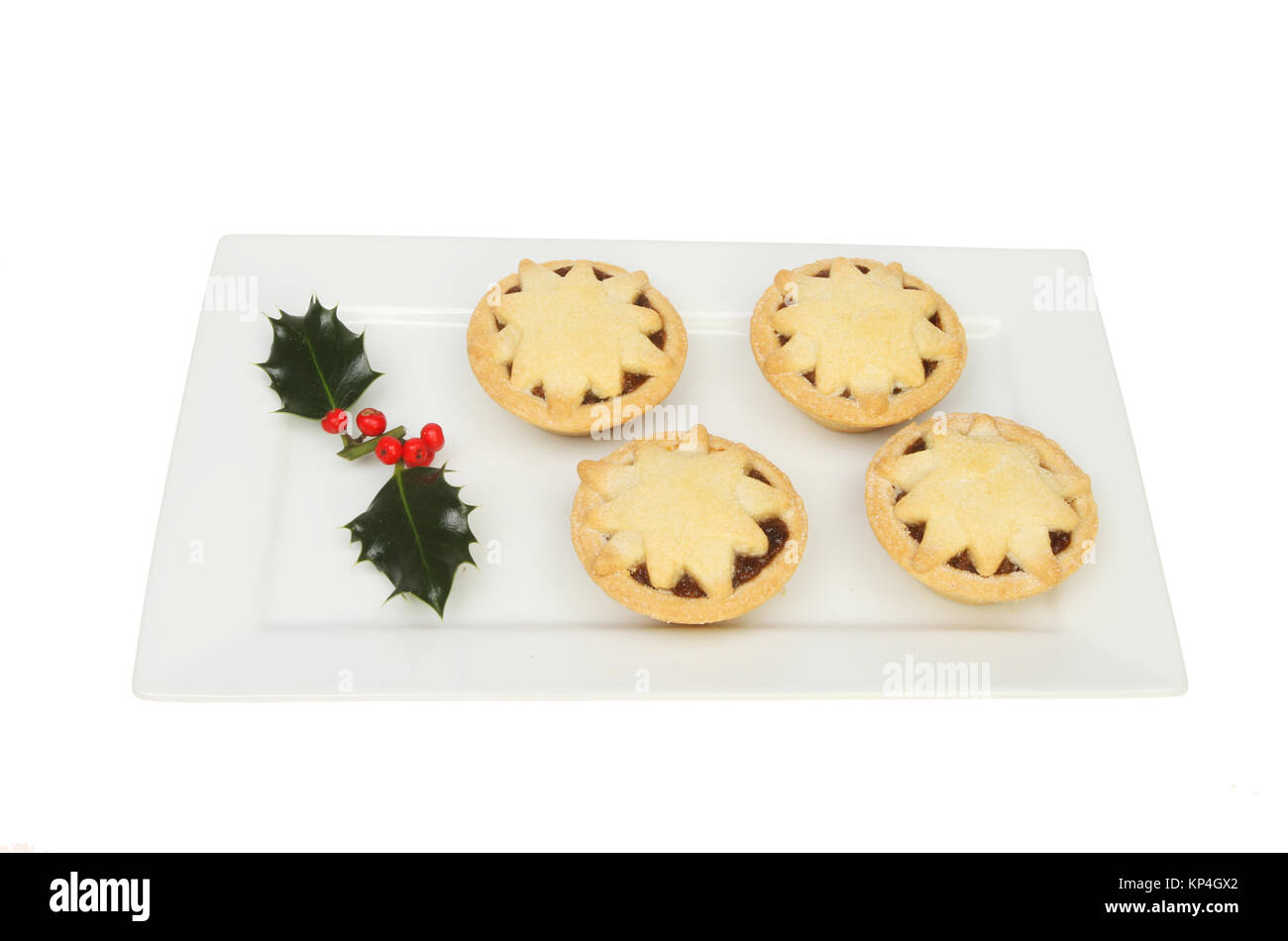 Mince pies decorated with stars on a rectangular plate with a sprig of ...