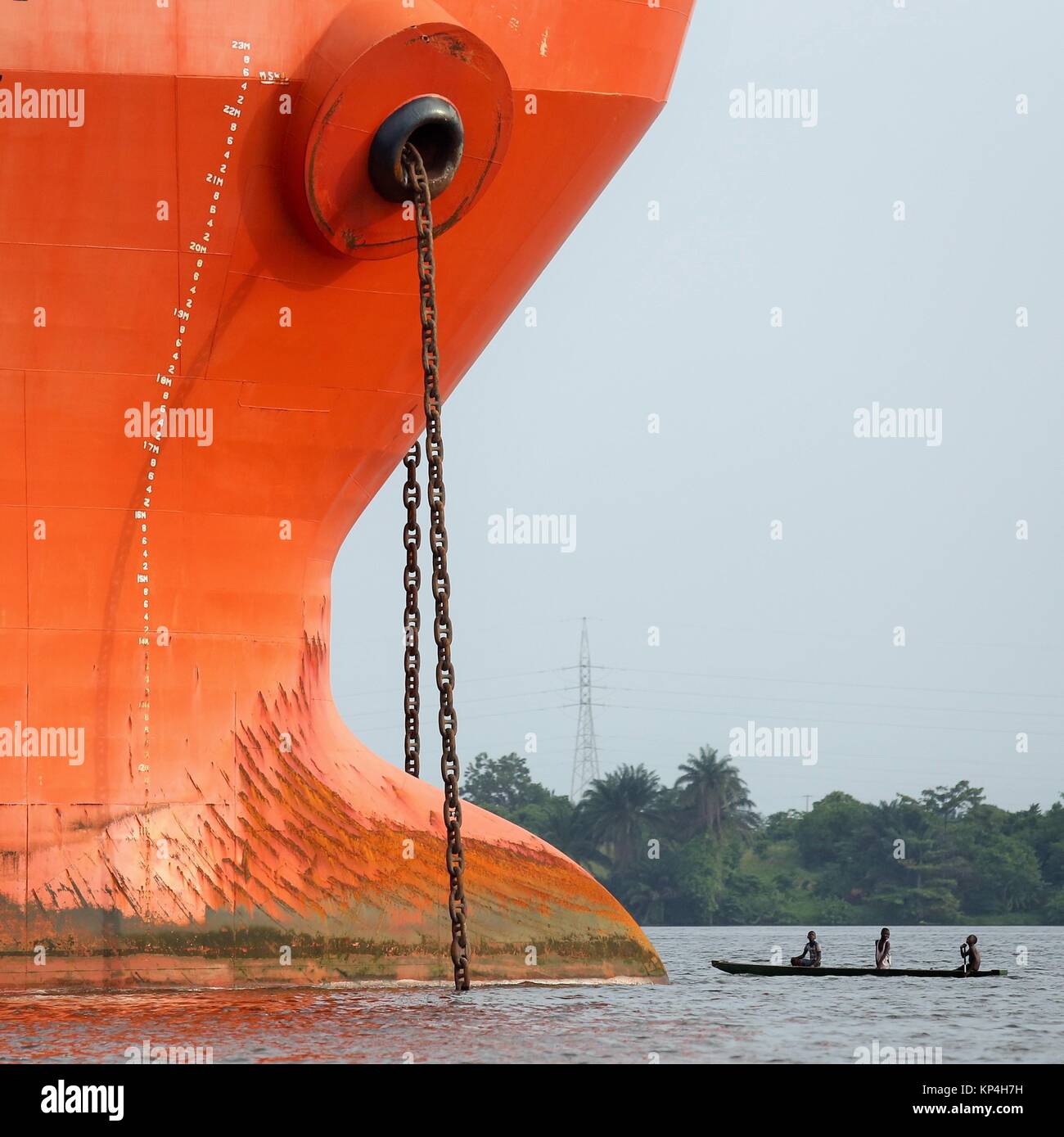 a small wooden boad face to face to the prow of a big ship Stock Photo