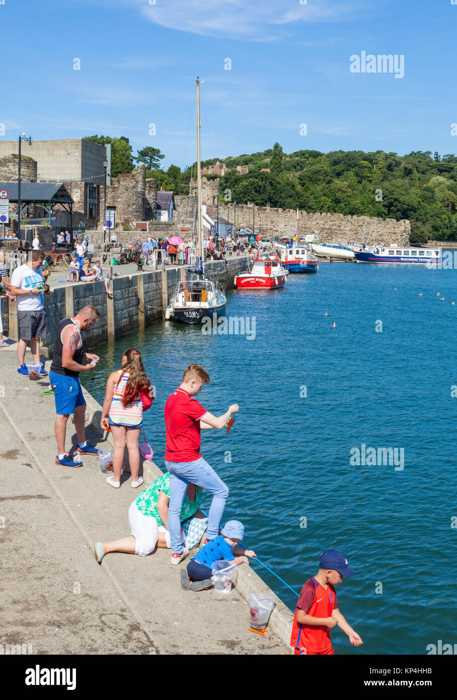 North wales conway north wales conwy north wales tourists adults and children fishing for crabs off the quayside harbour wall river Conwy Gwynedd uk Stock Photo
