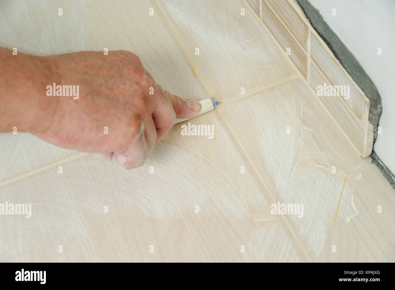 Workers hand smoothing the grout joints between tiles using a rubber stick Stock Photo Alamy