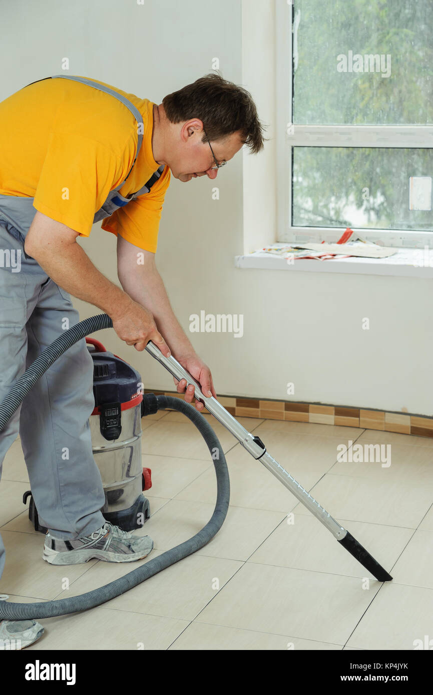 Worker cleans seams between tiles using a vacuum cleaner Stock Photo