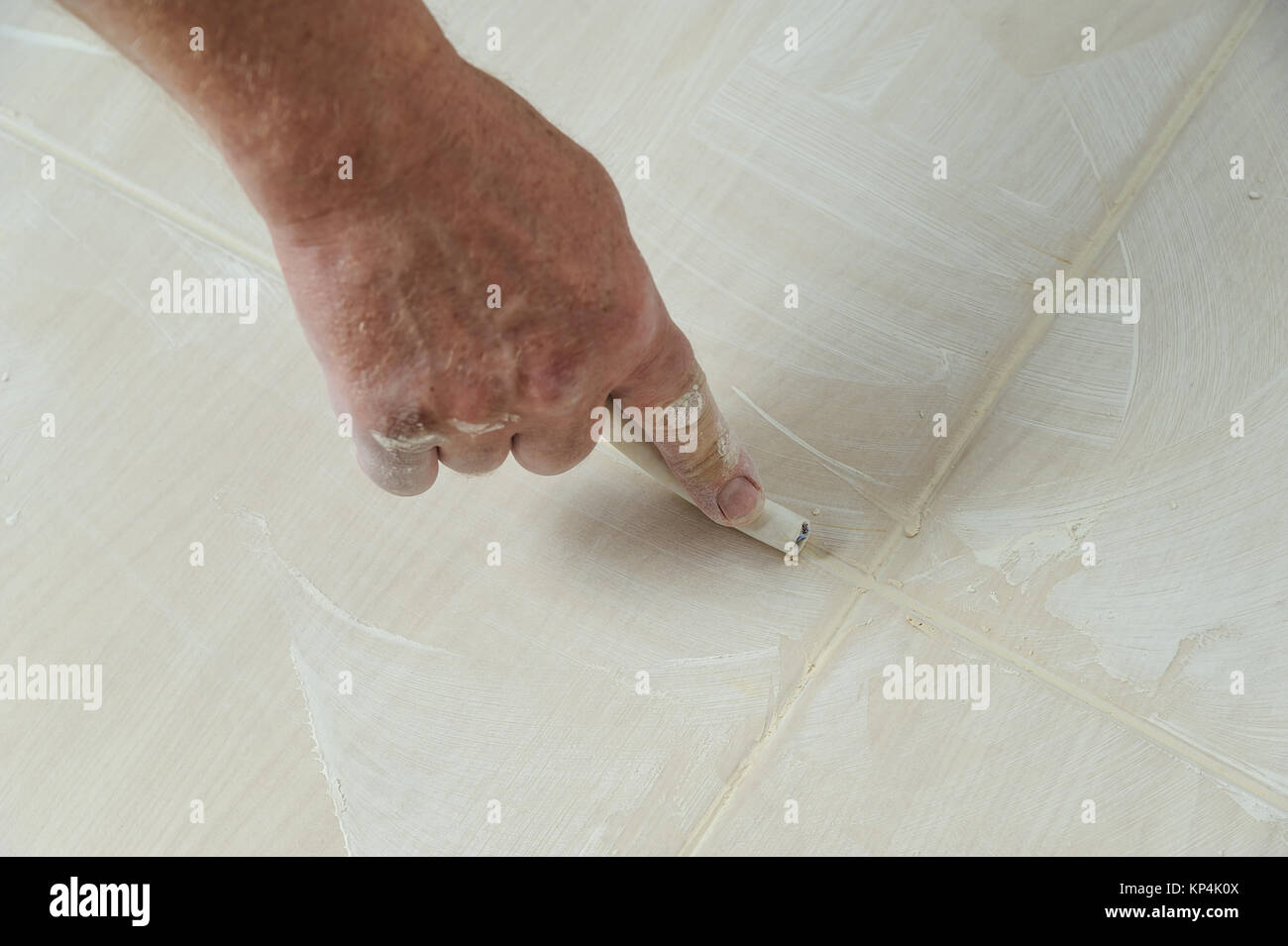 Workers hand smoothing the grout joints between tiles using a rubber