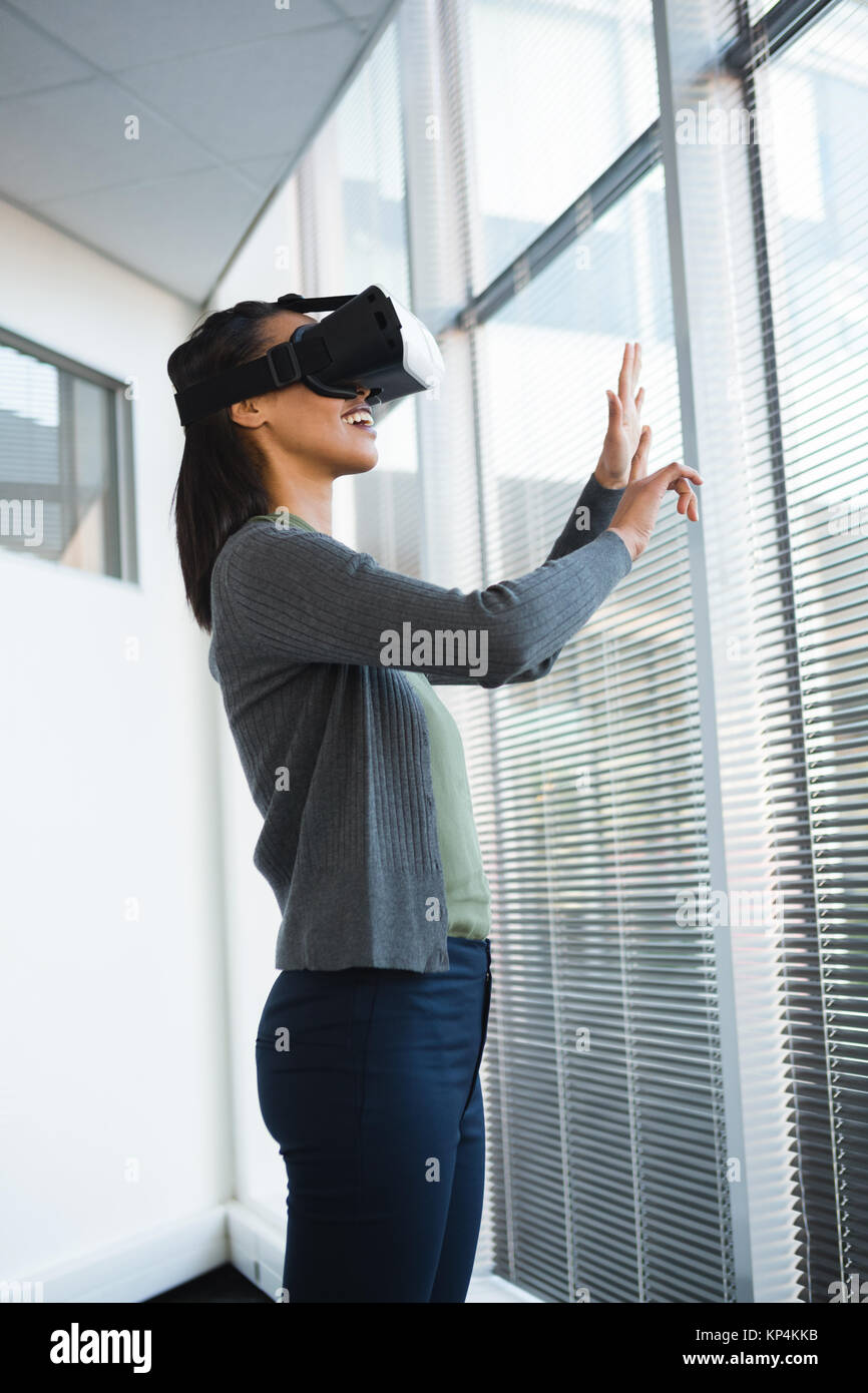 Female executive using virtual reality headset in office Stock Photo ...