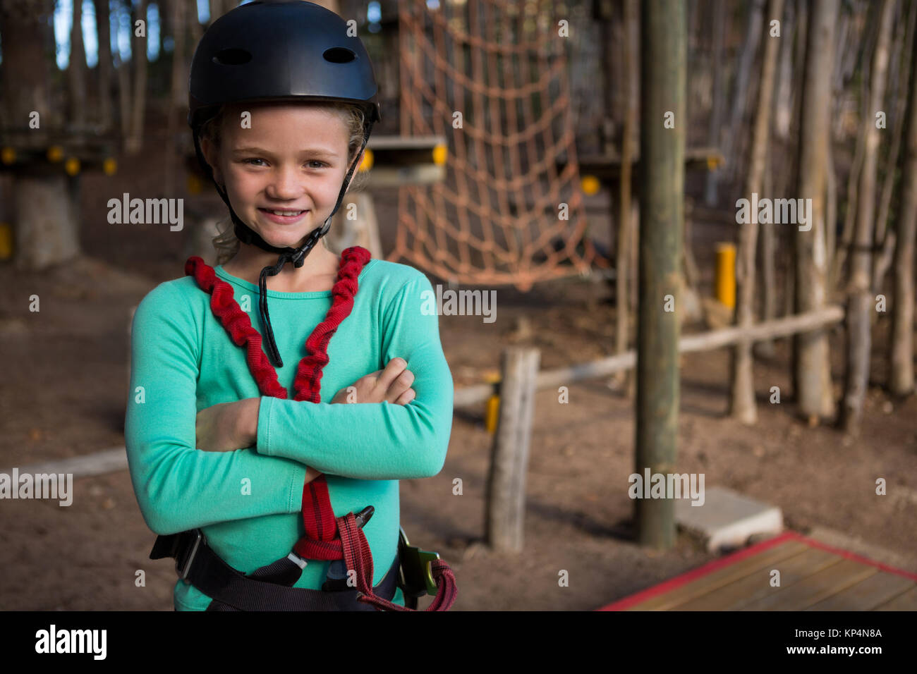 Portrait of little girl folding her hands wearing helmet and harness in the forest Stock Photo