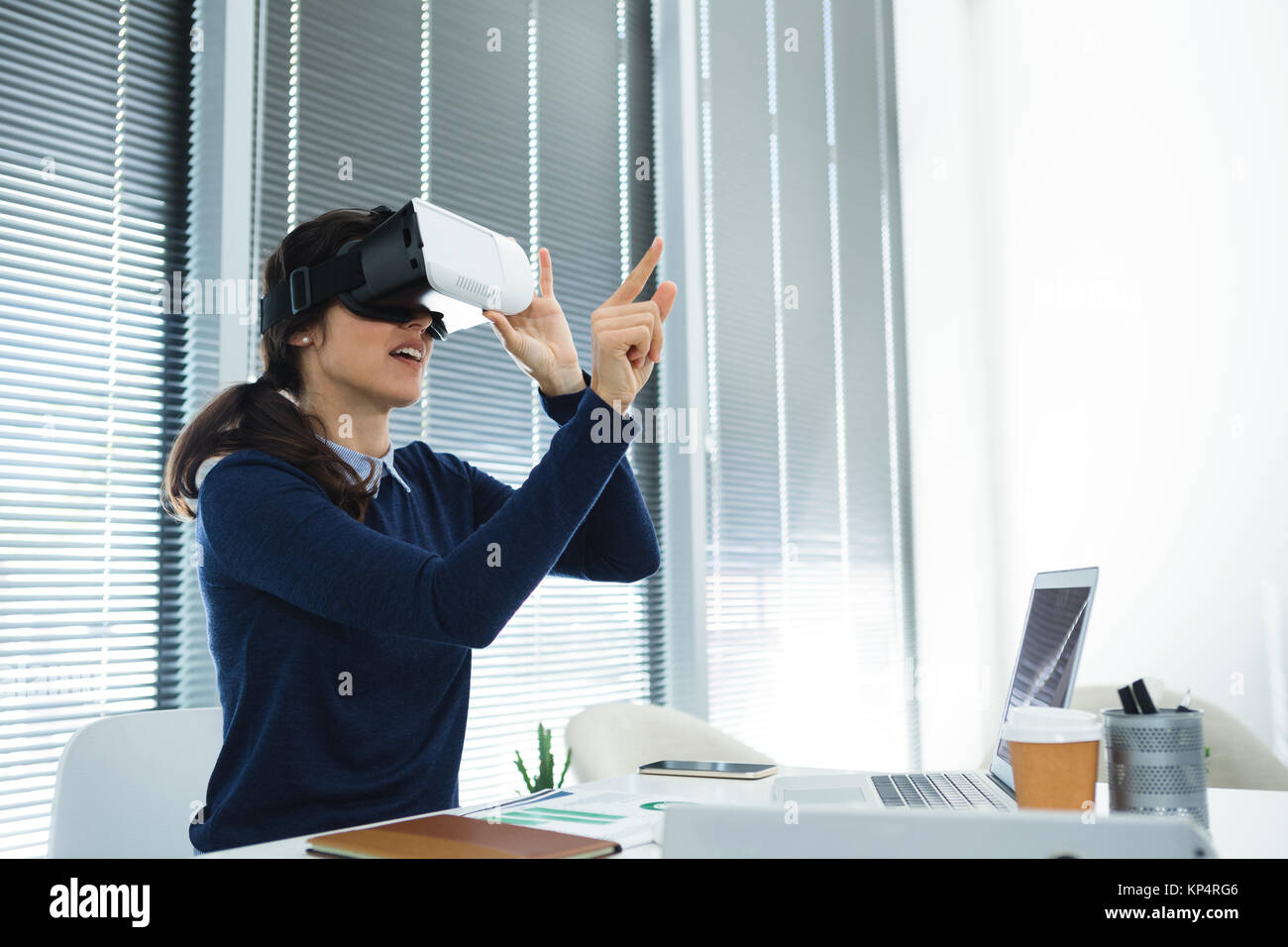 Female executive using virtual headset at desk in office Stock Photo ...